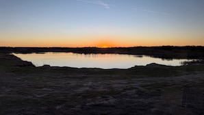 A natural landscape with a body of water, a clear sky, and a visible contrail.