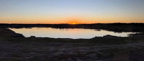 A natural landscape with a body of water, a clear sky, and a visible contrail.
