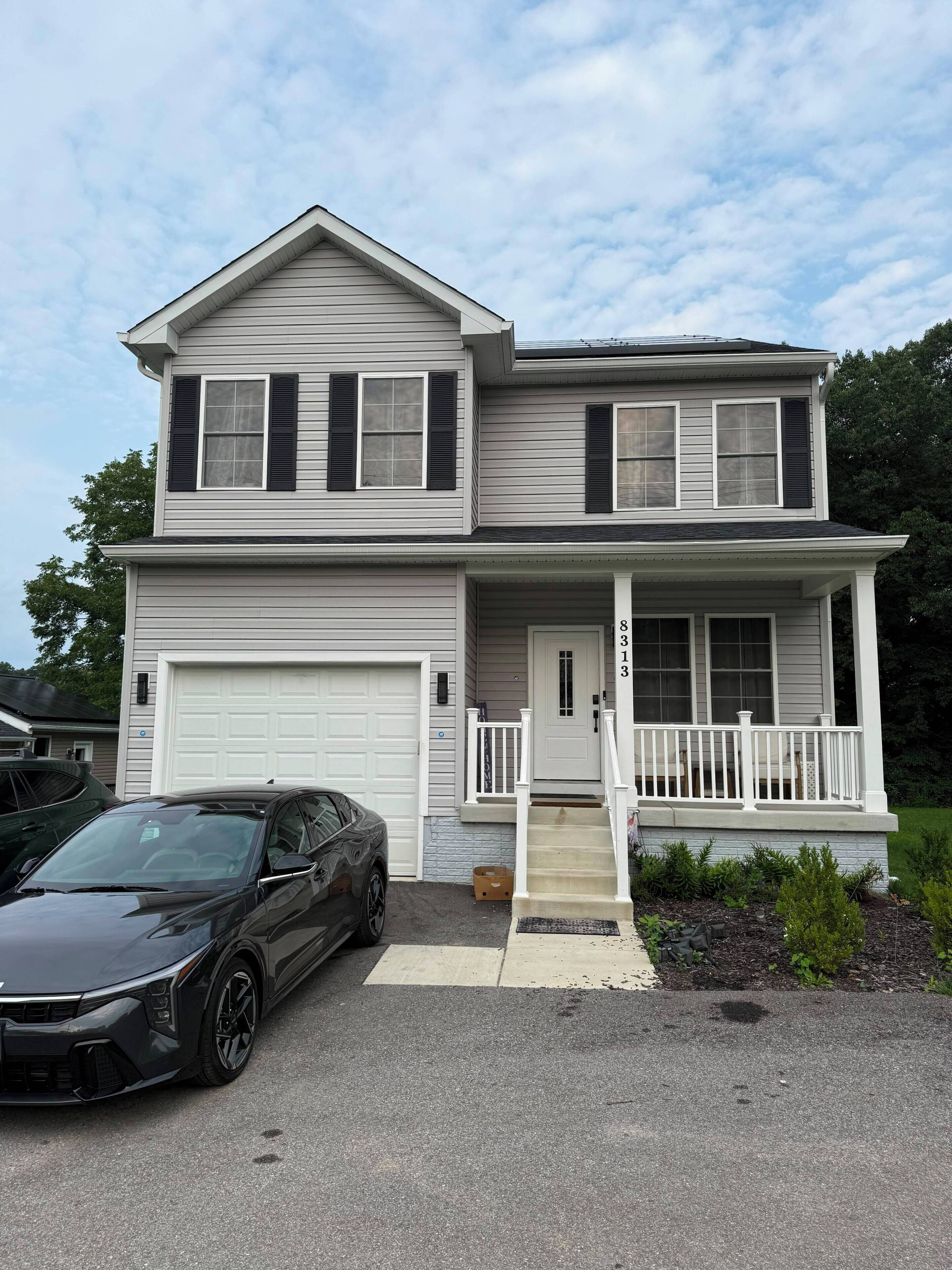 A two-story house with a garage, a front porch, and a driveway.