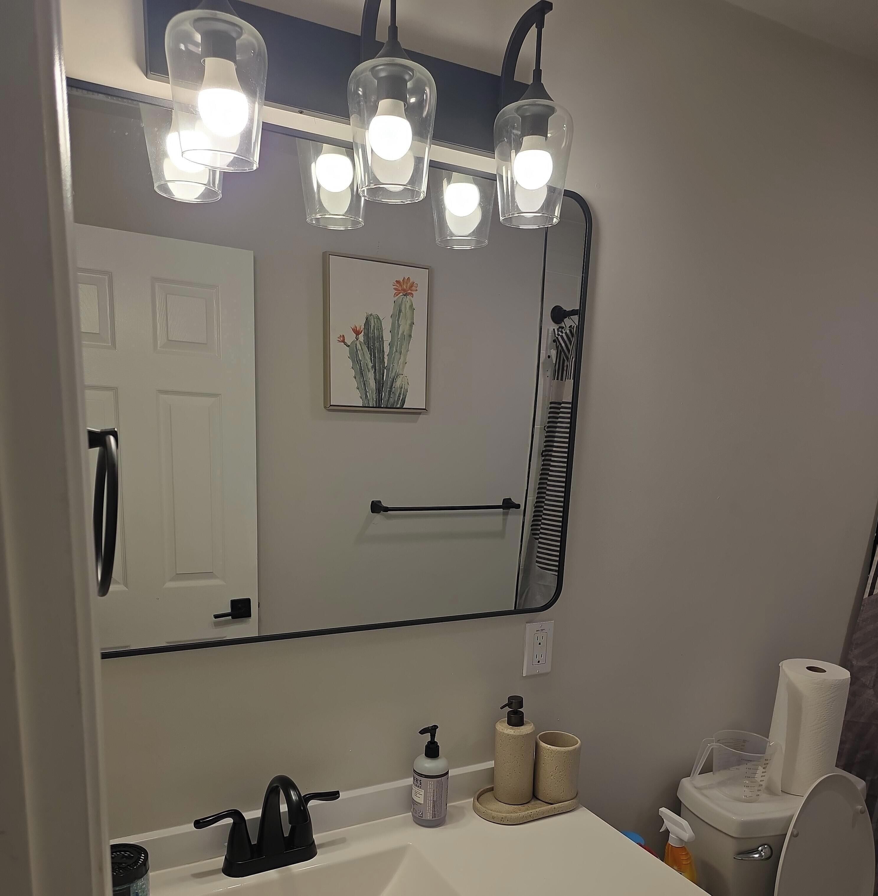 A bathroom with a large mirror, a sink, a toilet, and a shower.