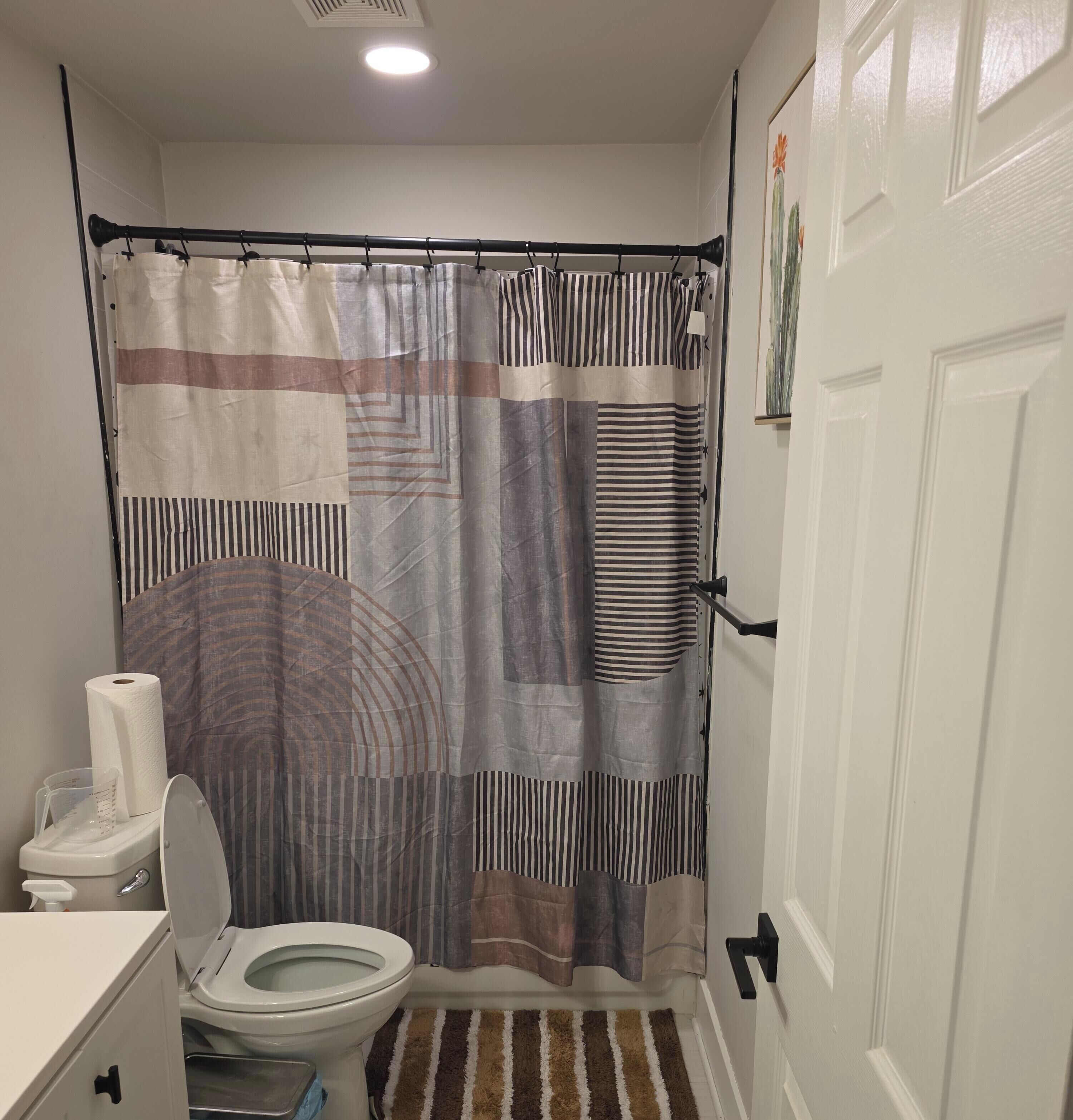 A bathroom with a toilet, a shower curtain, and a door.