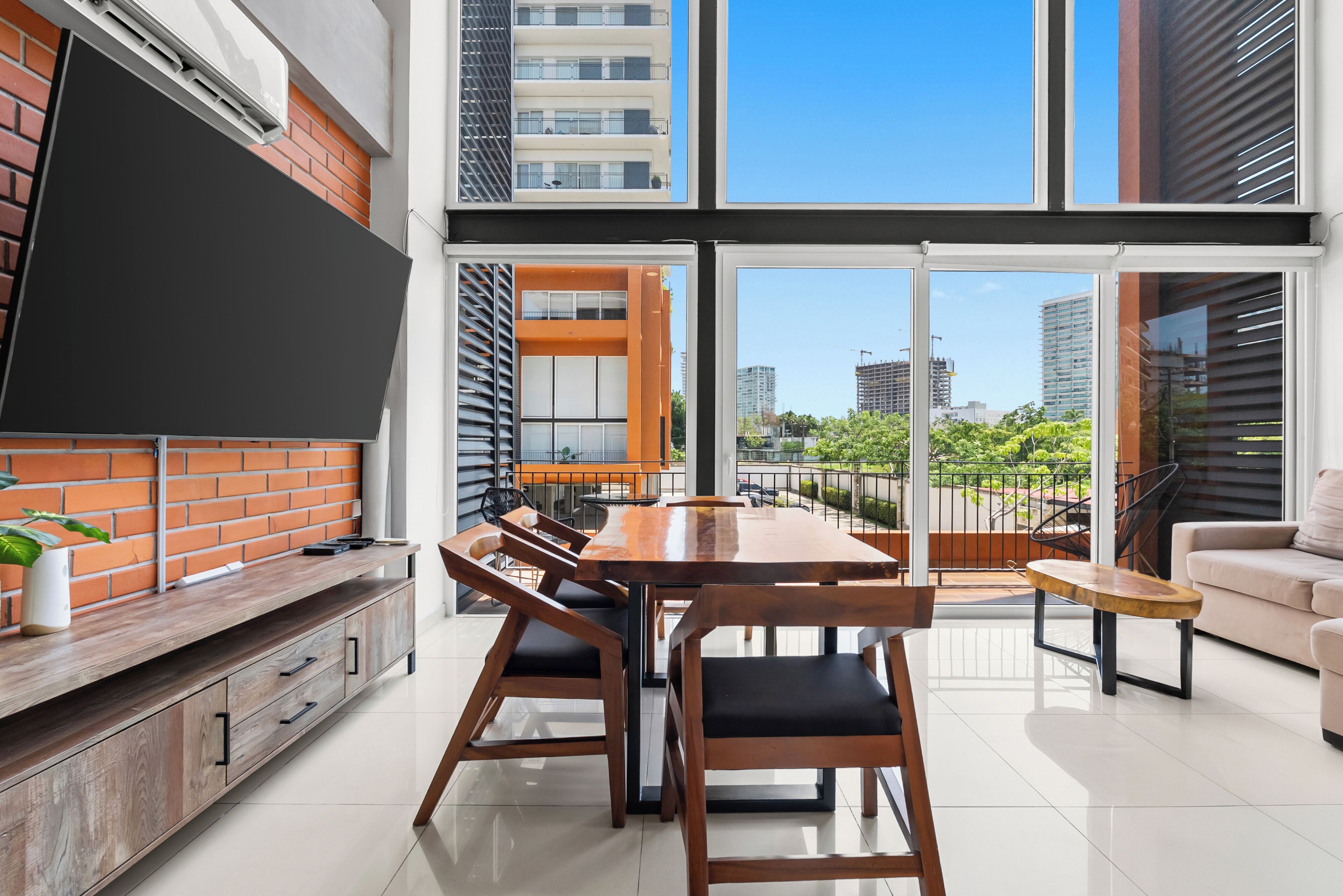 A modern kitchen with a dining area, large windows, and a view of the cityscape.