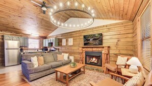 Ein gemütliches Blockhaus-Interieur mit Kamin, Holzwänden, einer Couch und einem Essbereich.