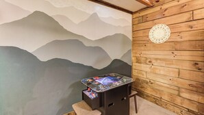 Ein Zimmer mit einer Bergwandmalerei, einem kleinen Tisch mit einem Bildschirm und einer Holzwand.