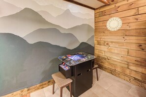 Ein Zimmer mit einer Bergwandmalerei, einem kleinen Tisch mit einem Bildschirm und einer Holzwand.