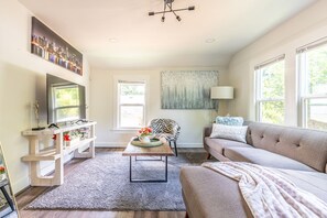 Ein Wohnzimmer mit einer Couch, einem Couchtisch, einem Fernseher und einem Gemälde an der Wand.