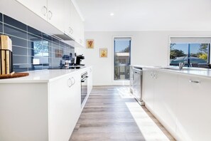 Una cocina moderna con muebles blancos, una isla central y vistas al exterior a través de una ventana.