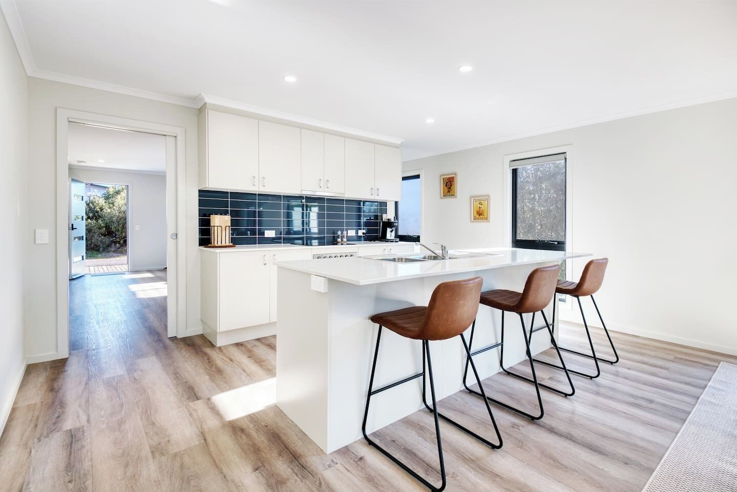 A modern kitchen with a large island, bar stools, and a view of the outdoors.