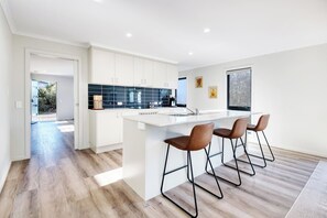 A modern kitchen with a large island, bar stools, and a view of the outdoors.