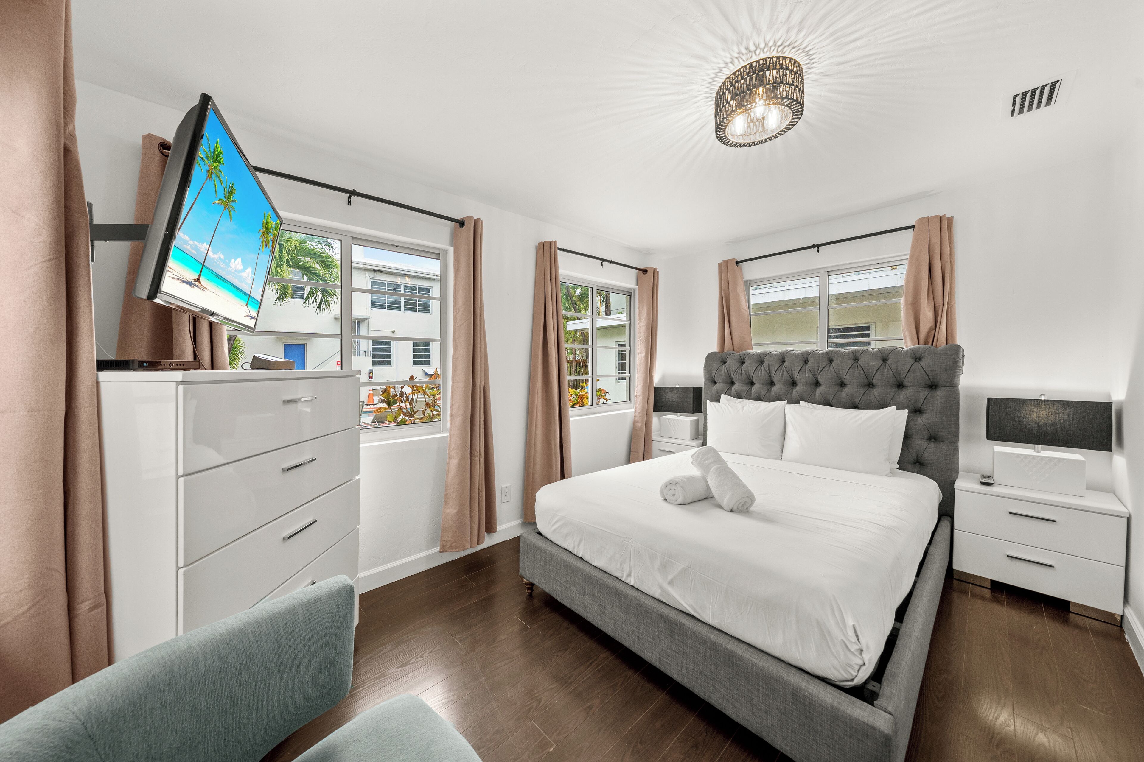 A hotel room with a bed, a TV, a desk, and a chair.