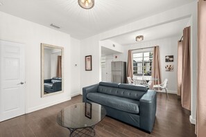 A modern living room with a sofa, a glass coffee table, and a large mirror. - Adorable 1-bedroom apartment with Pool in Miami Beach (Miami Beach)