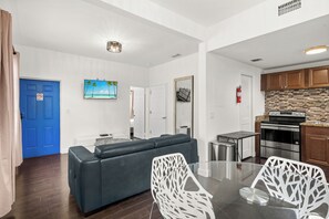 Ein modernes Wohnzimmer mit einer blauen Tür, einem Sofa, einem Glastisch und weißen Stühlen.