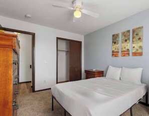A bedroom with a bed, a wardrobe, a ceiling fan, and a door. - Your Colorado Springs Home Base! (Colorado Springs)