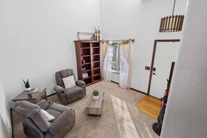 A living room with a gray sofa, a recliner, a wooden coffee table, and a bookshelf. - Your Colorado Springs Home Base! (Colorado Springs)