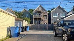 A residential street with houses, a parked truck, and blue trash bins. - 2BR Avondale Apt: Free Parking + Steps to Blueline (Chicago)