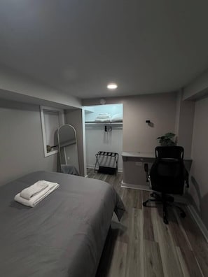 Ein kleines Hotelzimmer mit einem Bett, einem Schreibtisch, einem Stuhl und einem kleinen Fenster.