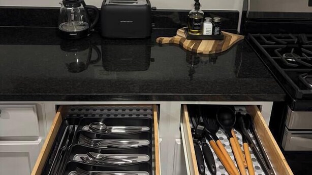 A kitchen with white cabinets, a black countertop, a toaster, a coffee maker, and a drawer with utensils. - 2BR Avondale Apt: Free Parking + Steps to Blueline (Chicago)