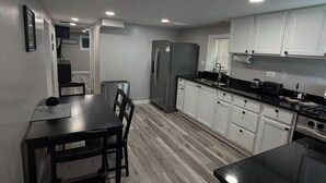 A modern kitchen with a dining table, chairs, cabinets, and a refrigerator. - 2BR Avondale Apt: Free Parking + Steps to Blueline (Chicago)