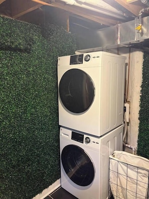 Een gestapelde wasmachine en droger in een wasserij met een groene kunstmatige wand.