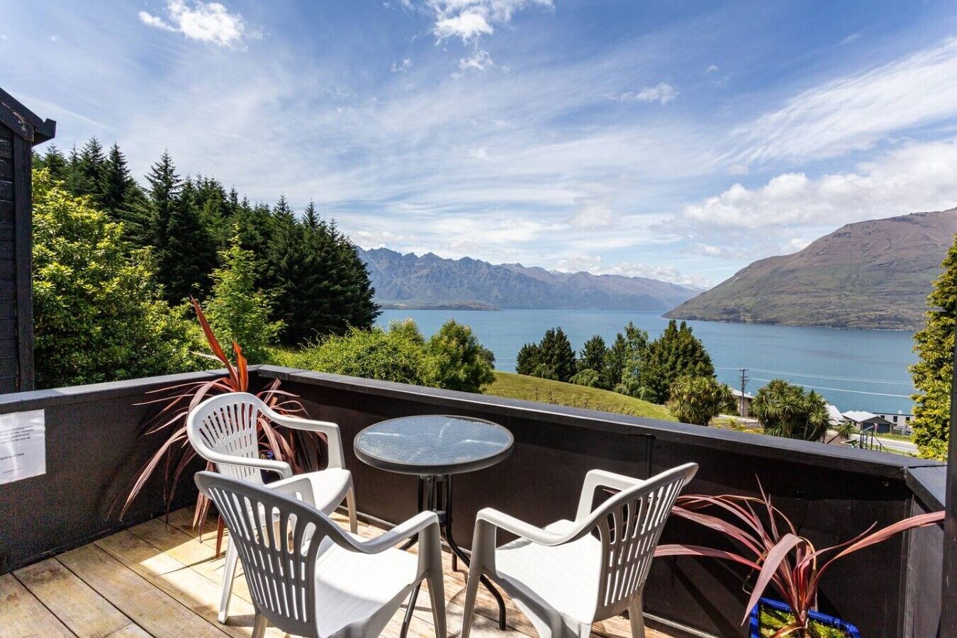 A balcony with a table and chairs, overlooking a lake and mountains.