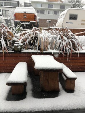 Ein verschneiter Außenbereich mit Bänken und einer Holzverkleidung.