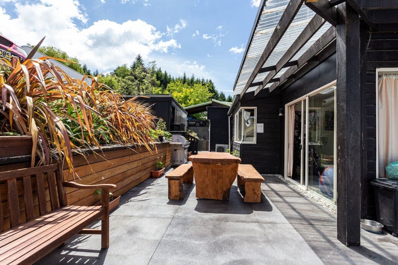 Un patio exterior con bancos de madera y una zona de barbacoa.