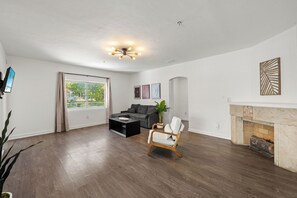 A living room with a fireplace, a sofa, a coffee table, and a decorative chair. -  4-bedroom 2 Baths with Pool in Steps to the Beach (Miami Beach)