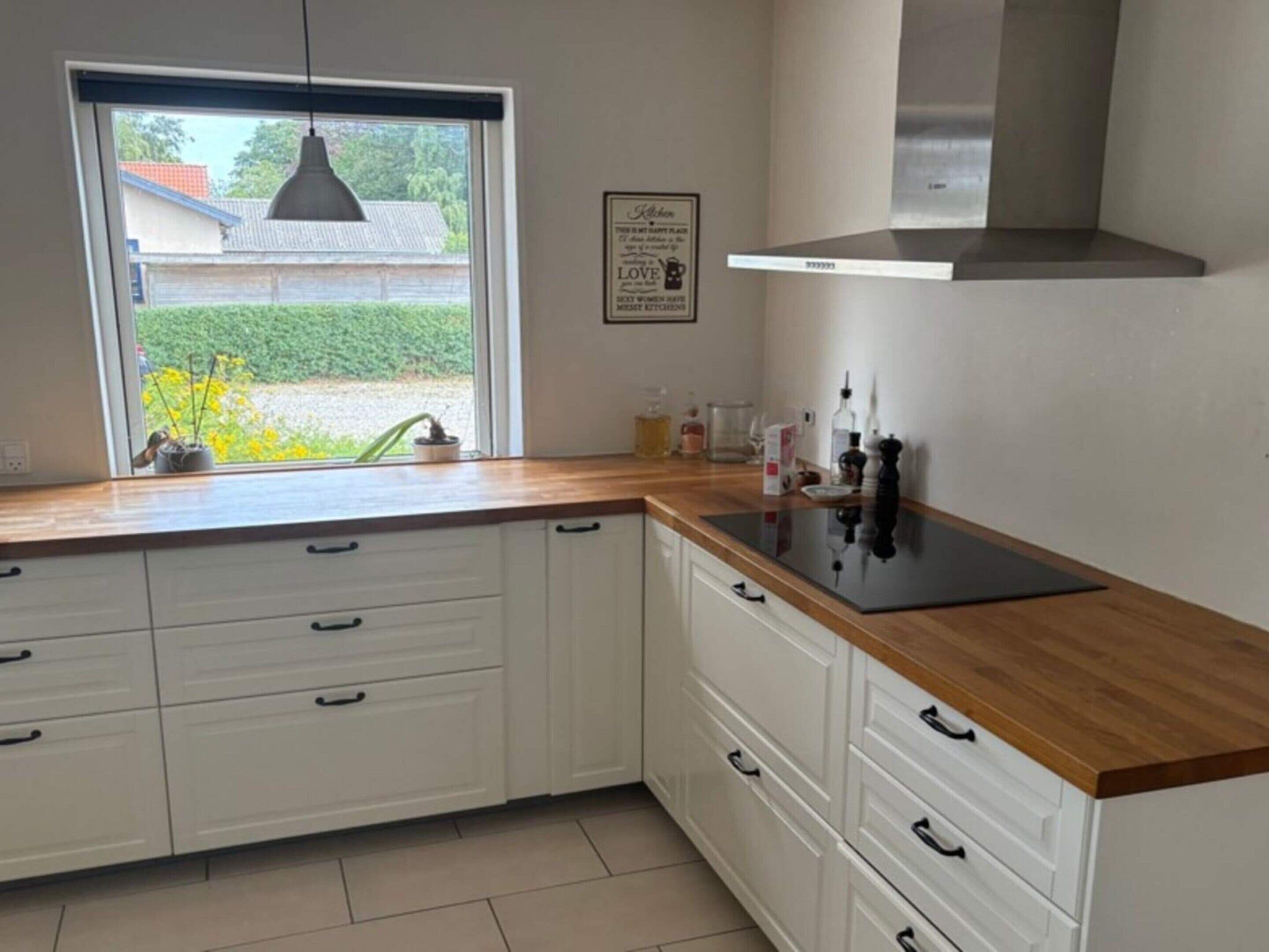 A kitchen with white cabinets, a black countertop, and a stainless steel range hood.
