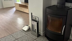 A room with a black wood-burning stove, a white door, and a small wooden cabinet. - 4 Person Holiday Home in Orum Djurs (Ørum Djurs)