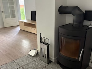 A room with a black wood-burning stove, a white door, and a small wooden cabinet. - 4 Person Holiday Home in Orum Djurs (Ørum Djurs)