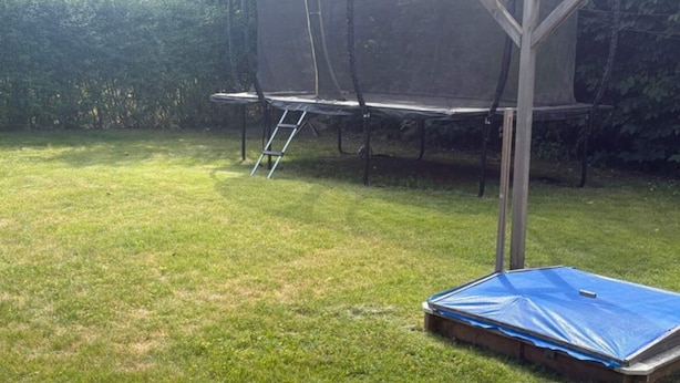 A trampoline with a safety net, a ladder, and a blue tarp on the ground. - 4 Person Holiday Home in Orum Djurs (Ørum Djurs)