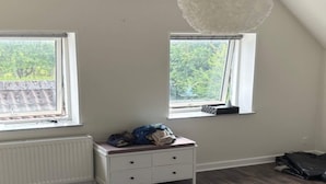 A room with two windows, a white radiator, a white dresser with drawers, and a hanging light fixture. - 4 Person Holiday Home in Orum Djurs (Ørum Djurs)