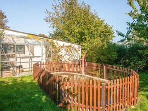 A fenced garden area with a greenhouse and a wooden fence. - 4 Person Holiday Home in Orum Djurs (Ørum Djurs)
