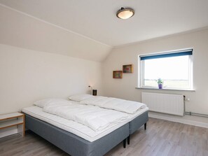 A bedroom with a bed, a window with a view, a radiator, and a small shelf. - 4 Person Holiday Home in Orum Djurs (Ørum Djurs)