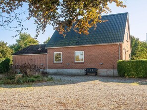 Un bâtiment en briques avec un toit en pente, deux fenêtres et un banc devant.