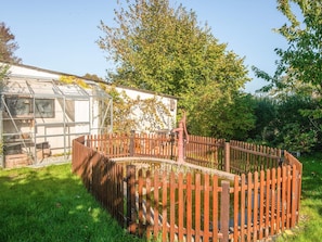 A fenced garden area with a greenhouse and a wooden fence.