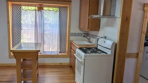 Une cuisine équipée d’une cuisinière, d’un four et d’une fenêtre avec des rideaux.