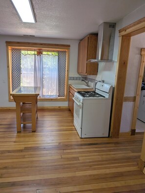 A kitchen with a stove, oven, and window with curtains. - Casa Tomas - Beautifully restored Adobe from the 1800's.  True NM. (Albuquerque)