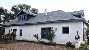 Une maison de plain-pied avec un toit à pignon, une cheminée et un petit porche.
