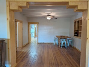 A spacious room with a wooden floor, a ceiling fan, and a dining area with a table and chairs. - Casa Tomas - Beautifully restored Adobe from the 1800's.  True NM. (Albuquerque)