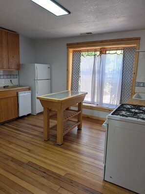A kitchen with wooden cabinets, a refrigerator, a stove, and a window with curtains. - Casa Tomas - Beautifully restored Adobe from the 1800's.  True NM. (Albuquerque)