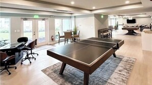 A modern indoor space with a ping pong table, a desk with chairs, and a television. - Beautiful Beachfront 2 Bedroom 2 Full Baths (Bonita Springs)