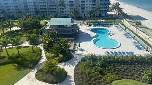 A resort with a large pool, palm trees, and a beach view. - Beautiful Beachfront 2 Bedroom 2 Full Baths (Bonita Springs)