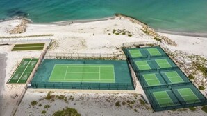A tennis court complex with multiple courts, surrounded by a sandy beach and ocean. - Beautiful Beachfront 2 Bedroom 2 Full Baths (Bonita Springs)