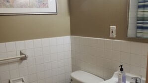 A bathroom with a toilet, sink, and a clock on the wall.