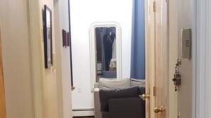 A narrow hallway with wooden flooring, a mirror, and a door on the right.