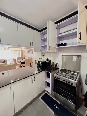 A compact kitchen with white cabinets, a gas stove, and a dining area with a table and chairs.