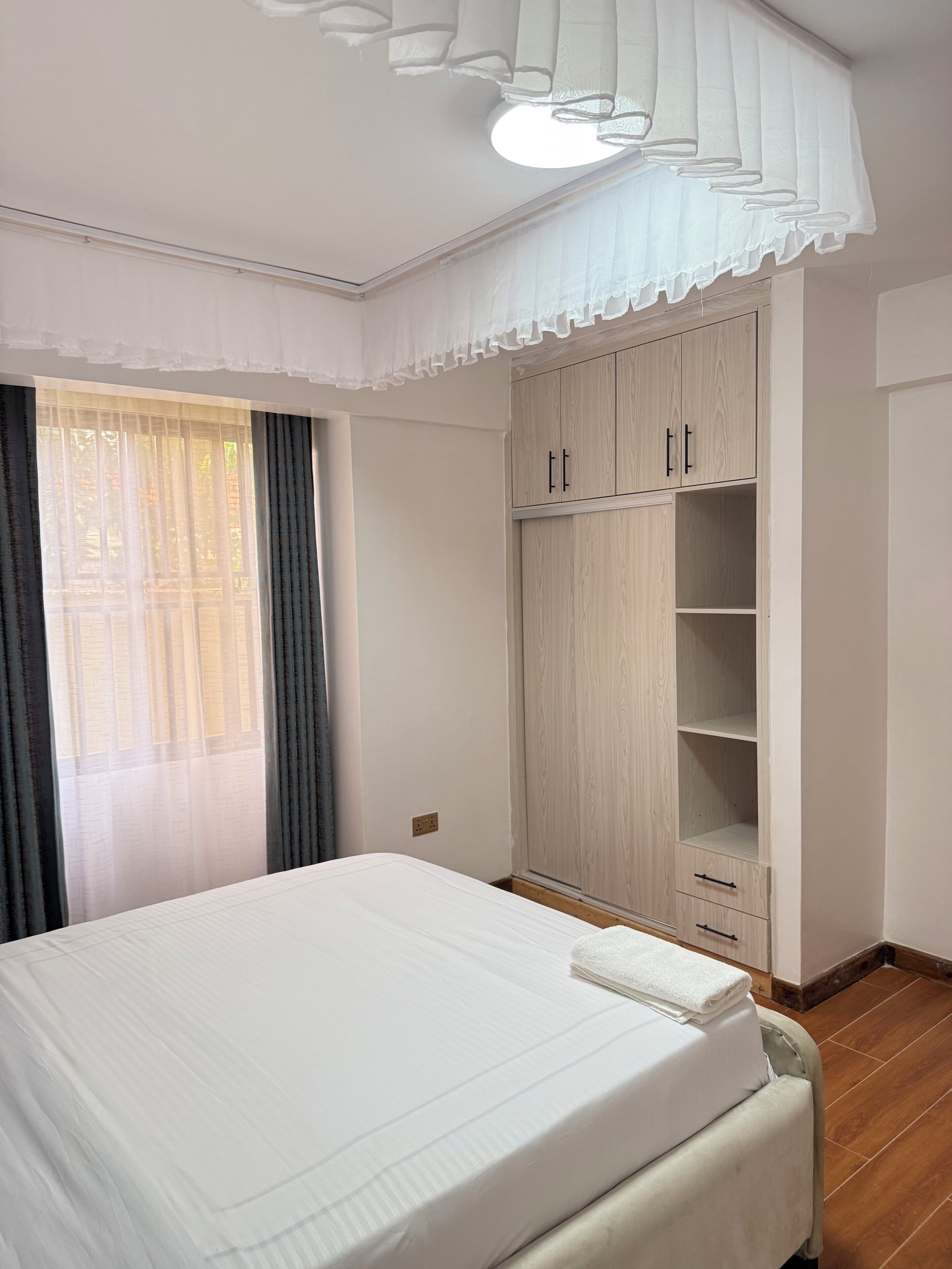 Quarto com uma cama, um guarda-roupa e uma janela com cortinas.