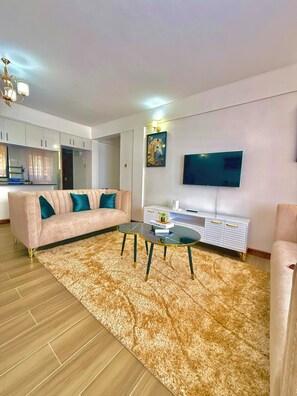 A modern living room with a sofa, coffee table, and a flat-screen TV mounted on the wall.