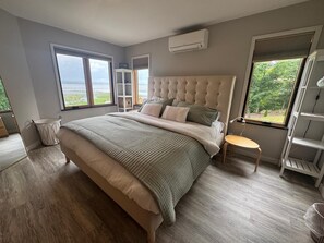 Ein Schlafzimmer mit einem großen Bett, einem Fenster mit Aussicht, einer eingebauten Ablagefläche und einer Klimaanlage.